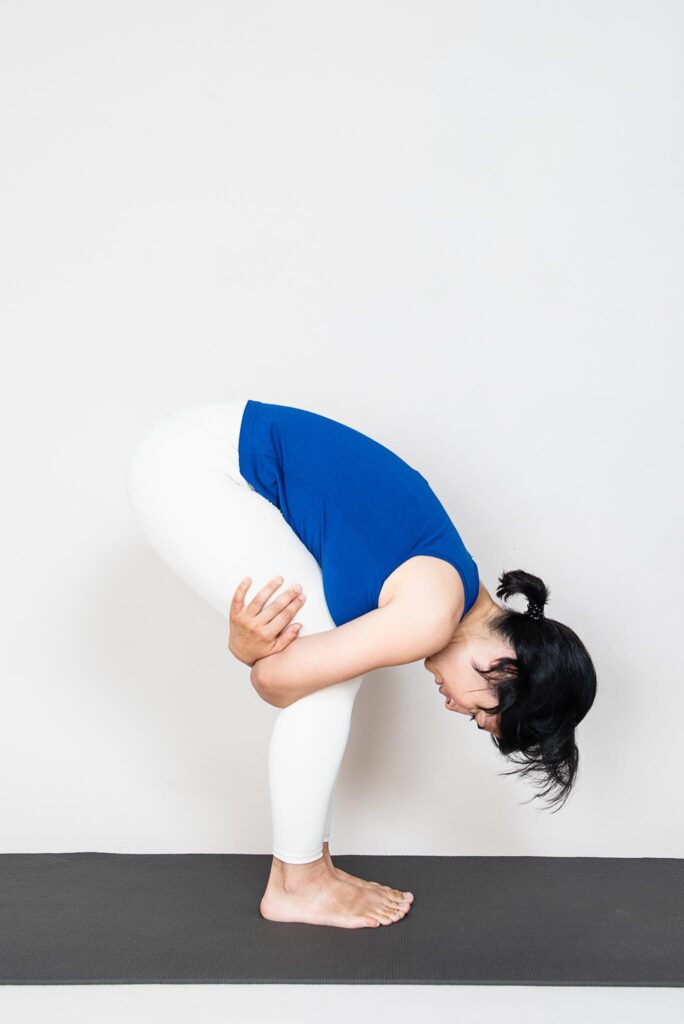 Woman practicing Uttanasana with bent legs.