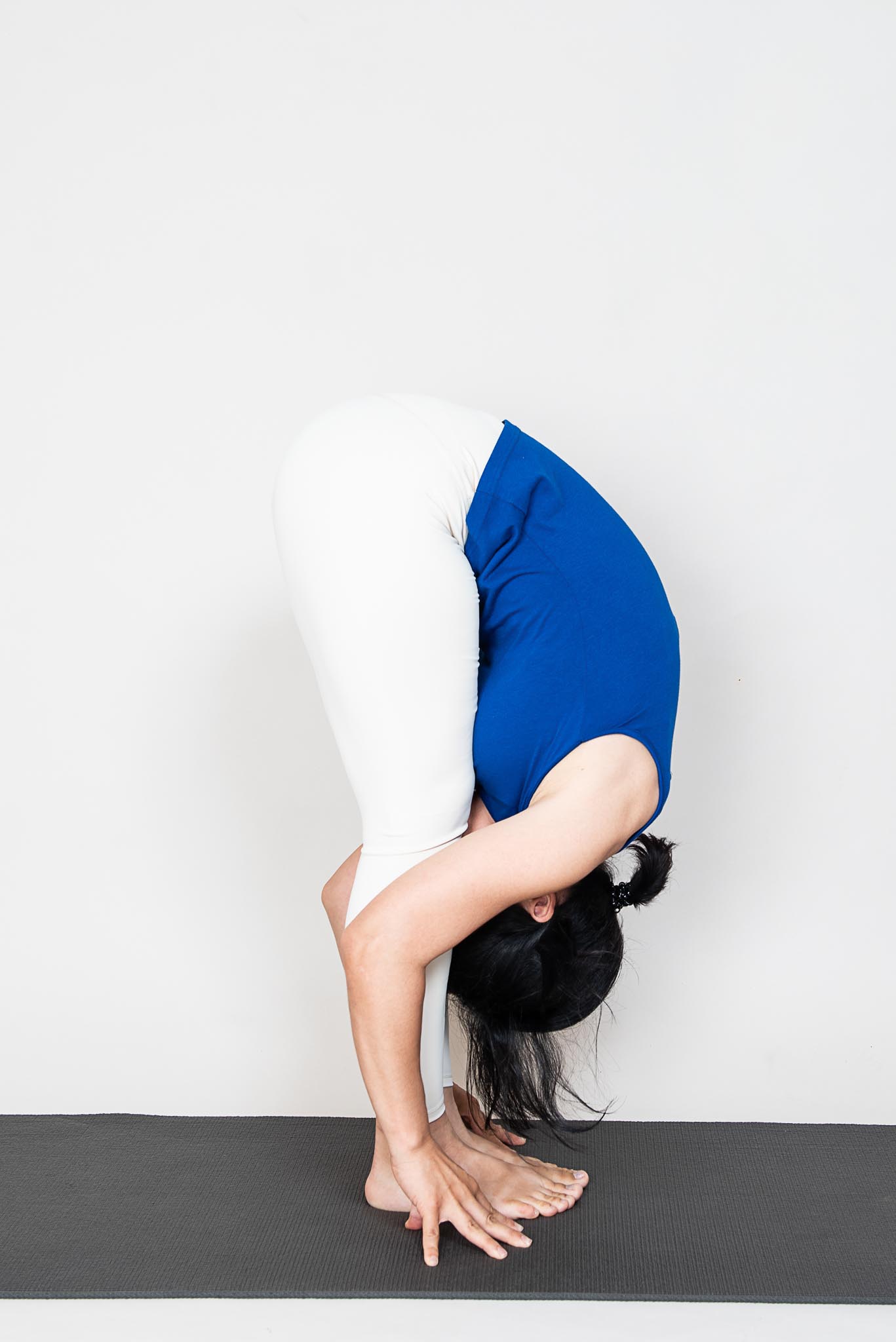 Woman practicing Uttanasana (Standing Forward Bend) with straight legs.