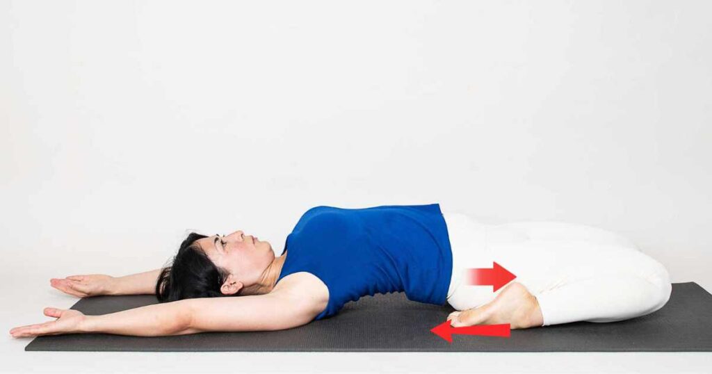 Woman practicing reclining hero pose (supta virasana) with arrows to explain the alignment.